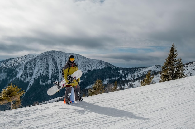 Mężczyzna snowboardzista z flagą słowacji na stoku ośrodka narciarskiego piękny krajobraz gór na tle