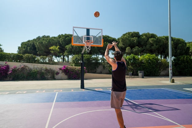 Mężczyzna sportowiec grający w koszykówkę rzucający piłką na plac zabaw