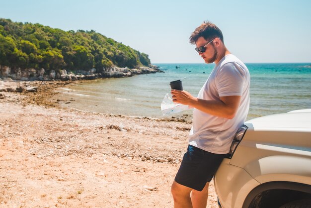 Mężczyzna sprawdza na mapie w miejscu przeznaczenia maski samochodu plaża morze na tle czasu letniego