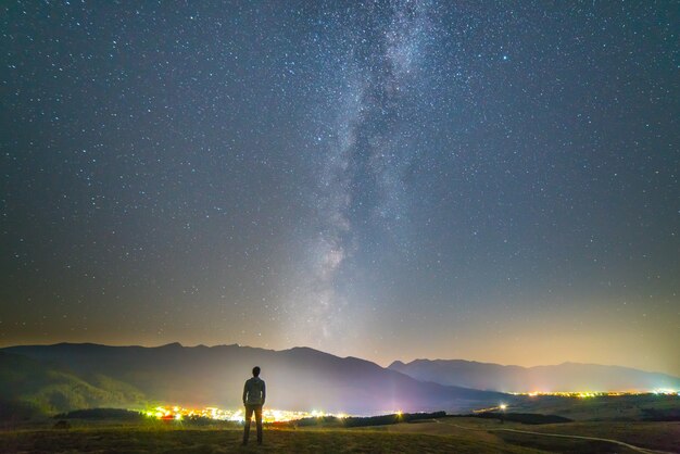 Mężczyzna stoi na tle świateł miasta. pora nocna