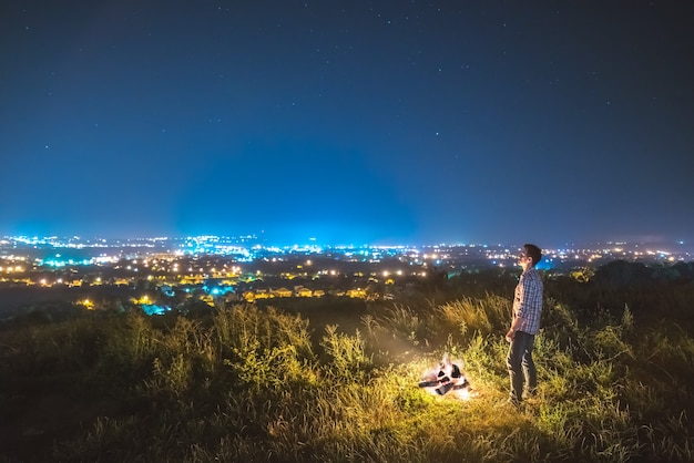 Mężczyzna stoi przy ognisku na tle miasta. pora nocna