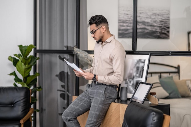 Mężczyzna stojący bokiem do aparatu, czytający gazetę