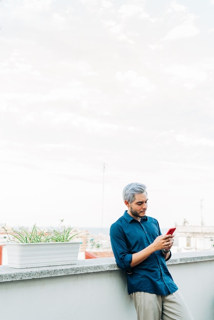 Mężczyzna stojący na balkonie i przy użyciu telefonu