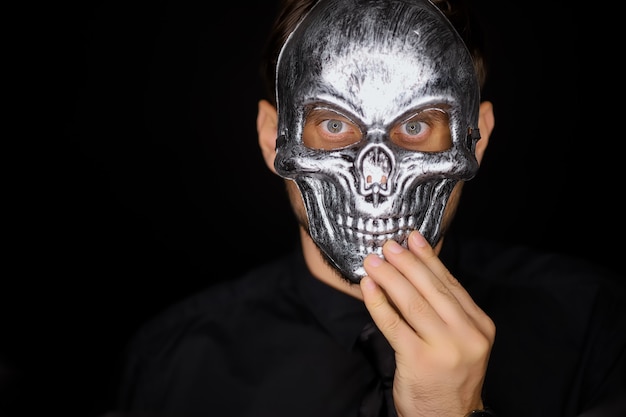 Zdjęcie mężczyzna stojący na czarnym tle nosi maskę szkieletu