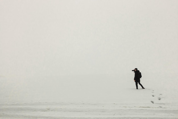 Mężczyzna stojący na lodzie mglisty poranek prosta minimalistyczna fotografia jedna osoba