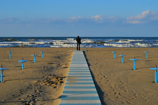 Zdjęcie mężczyzna stojący na plaży przed niebem