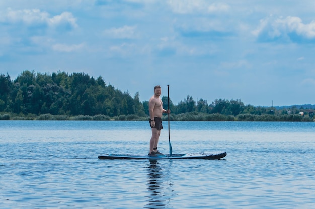 Mężczyzna stojący na supboardzie na środku jeziora