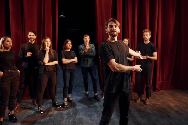 Zdjęcie mężczyzna stojący przeciwko ludziom grupa aktorów w ciemnych ubraniach na próbie w teatrze