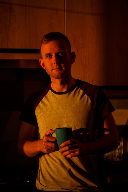 Mężczyzna Stojący Przed Oknem W świetle Zachodzącego Słońca Pije Kawę W Swojej Kuchni
