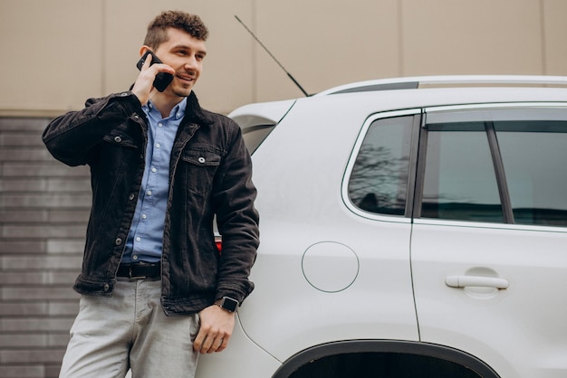 Mężczyzna stojący przy samochodzie i rozmawiający przez telefon