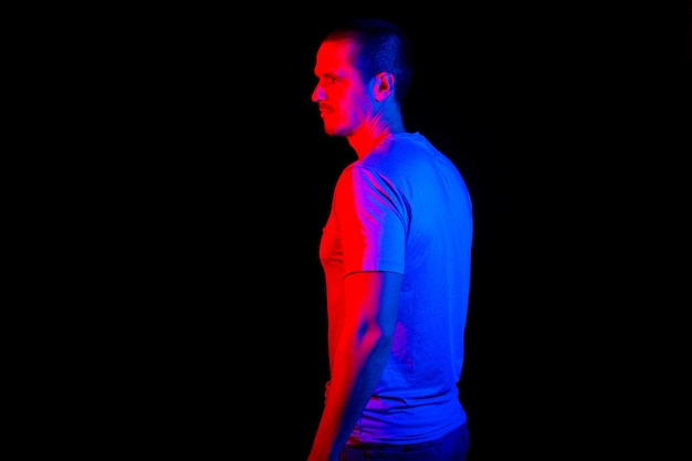 Mężczyzna stojący w studio pod czerwonymi i niebieskimi światłami na czarnym tle