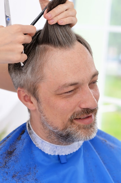 Mężczyzna strzyżący fryzurę od fryzjerki w salonie