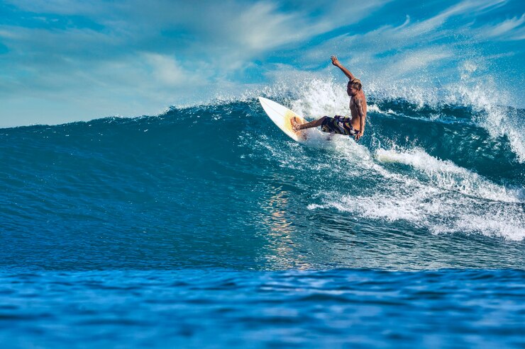 Zdjęcie mężczyzna surfer na niebieskiej fali w słoneczny dzień