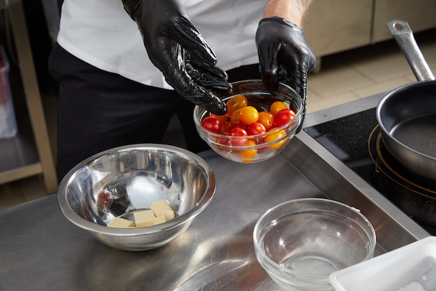 Mężczyzna szef kuchni przygotowuje sałatkę w kuchni dla smakoszy szefa kuchni robi pyszne danie w restauracji ser kuchenny