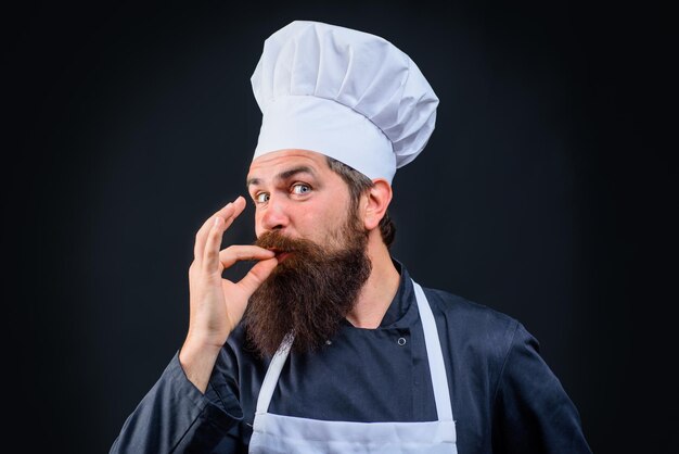 Mężczyzna szef kuchni w mundurze szefa kuchni w białym kapeluszu i fartuchu z doskonałym znakiem profesjonalnego szefa kuchni pokazującego