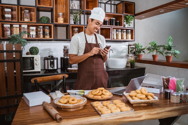 Mężczyzna szefa kuchni przygotowuje pączki w kuchni