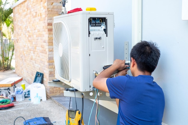 Mężczyzna-technik instalujący zewnętrzną jednostkę klimatyzatora do chłodzenia gospodarstwa domowego w lecie kompresor powietrza elektroniczny