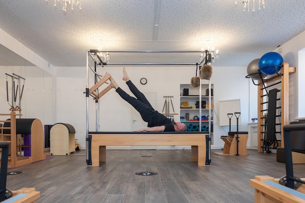Zdjęcie mężczyzna trener fitness pilates pokazuje ćwiczenia na specjalnych symulatorów pilates rozciąganie stoły