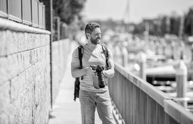 Mężczyzna trzyma aparat stojący na promenadzie Fotografia wakacyjna Fotografia podróżnicza