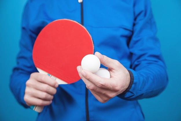 Zdjęcie mężczyzna trzyma rakietę tenisową i białą plastikową piłkę na niebiesko