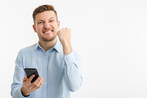 Mężczyzna trzyma smartfon w dłoni i cieszy się z udanej transakcji na giełdach kryptowalut Na białym tle na białym tle