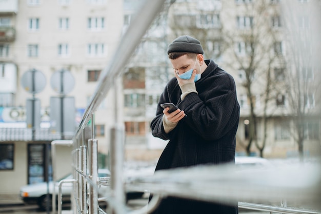 Mężczyzna trzyma smartphone i nosi maskę ochronną