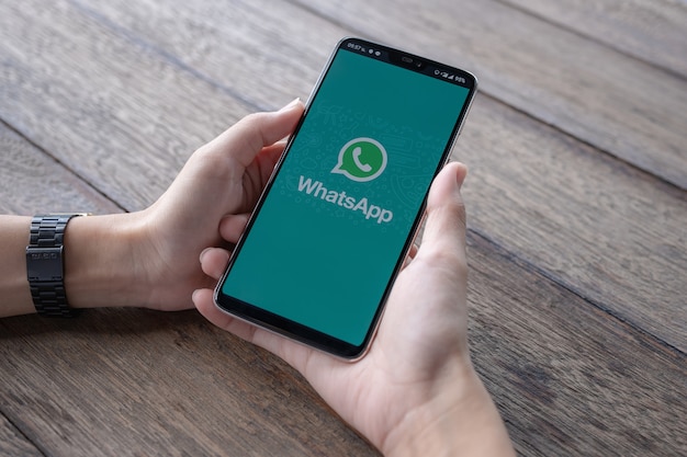 Mężczyzna trzyma Smartphone z otwartym WhatsApp na ekranie.