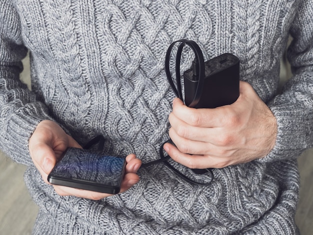 mężczyzna trzyma telefon i bank mocy