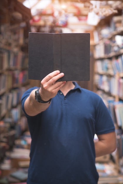 Zdjęcie mężczyzna trzyma w rękach książkę i czyta ją w bibliotece publicznej