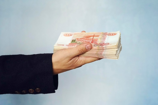 Mężczyzna trzyma w ręku ruble, biznesmen trzyma w ręku pieniądze