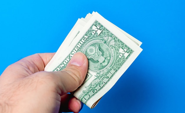 mężczyzna trzymający banknoty dolarowe na niebieskim tle