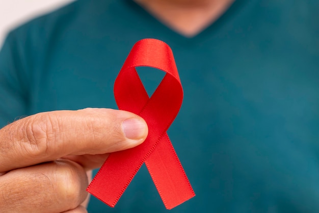 Mężczyzna trzymający czerwoną wstążkę świadomości AIDS Światowy Dzień Aids i Światowy Dzień Walki z Cukrzycą Koncepcja zapobiegania