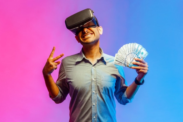 Mężczyzna trzymający iluzję dolarów bogatego milionera grającego w wirtualną grę pokazującą znak v