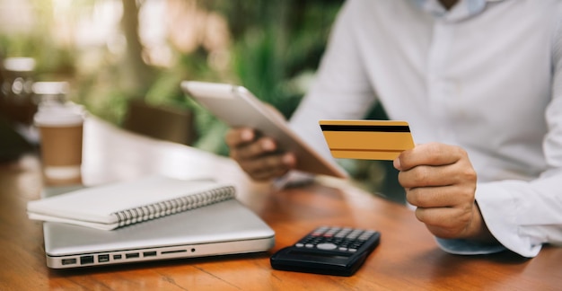 Mężczyzna trzymający kartę kredytową i używający tabletu pracujący w domu Zakupy online e-commerce bankowość internetowa wydawanie pieniędzy pracując z domu koncepcja Panoramiczny baner