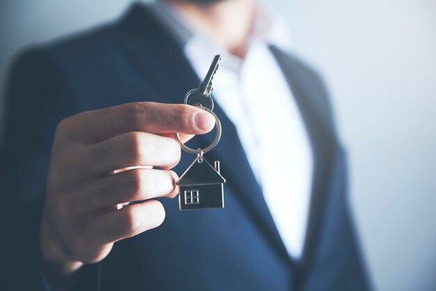 Mężczyzna trzymający klucz do domu na pęku kluczy w kształcie domu