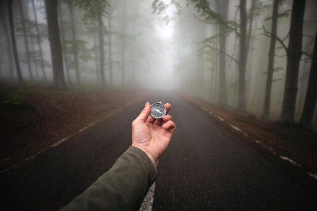 Zdjęcie mężczyzna trzymający kompas na drodze w mglistym lesie