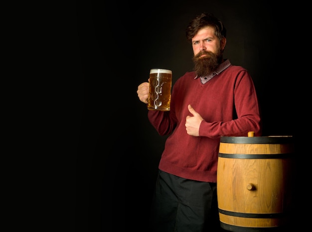 Zdjęcie mężczyzna trzymający kufel piwa szczęśliwy piwowar starszy mężczyzna pijący piwo z niespodzianką na twarzy koncepcja browaru piwo w niemczech portret przystojny młody mężczyzna degustujący piwo z beczki