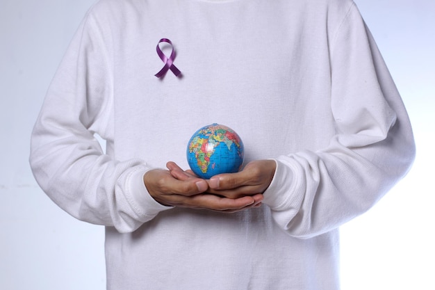 Mężczyzna trzymający kulę ziemską i noszący fioletową wstążkę na Światowy Dzień Walki z Rakiem