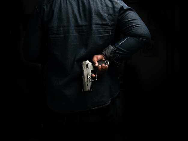 Mężczyzna Trzymający Pistolet Stojący W Pokoju W Czarnej Koncepcji Zabójstwa Przestępcy Morderstwa