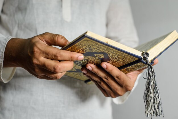 Zdjęcie mężczyzna trzymający świętą księgę z tytułem al koran.