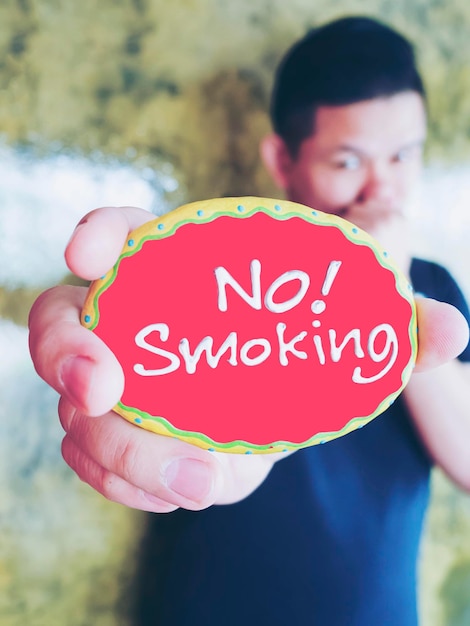 Zdjęcie mężczyzna trzymający tabliczkę z tekstem o zakazie palenia