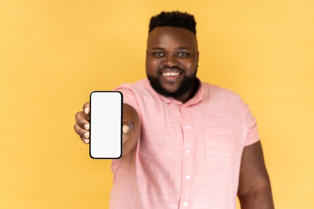 Mężczyzna trzymający telefon komórkowy, patrzący na kamerę pokazującą wyświetlacz telefonu komórkowego z miejscem na kopię