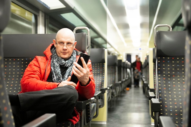 Zdjęcie mężczyzna trzymający telefon komórkowy siedząc w pociągu