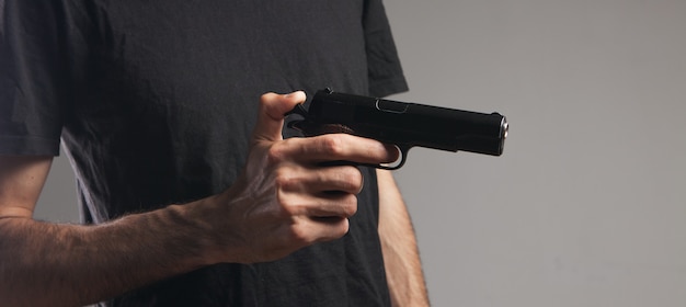 Mężczyzna trzymający w dłoni czarny pistolet grożący