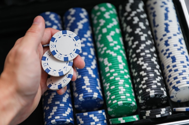 mężczyzna trzymający w dłoni stos żetonów do pokera.