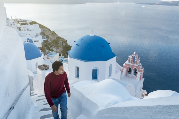 Mężczyzna turysta odwiedzający białą wioskę niebieskie kopuły w Oia Santorini Grecja Morze Śródziemne