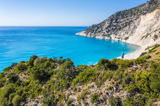 Mężczyzna turysta stojący na szczycie skały, cieszący się Myrtos Beach Cephalonia wyspa Grecja
