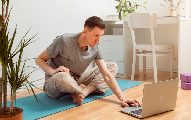 Zdjęcie mężczyzna uprawia jogę za pomocą laptopa.