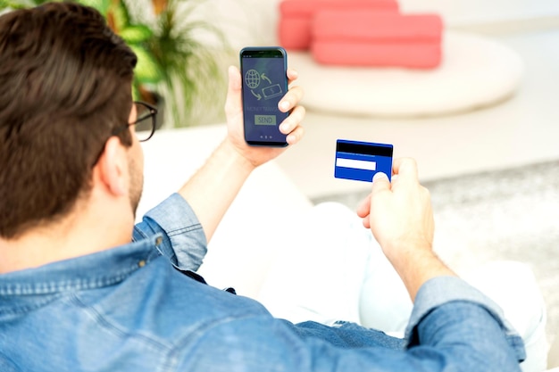 Zdjęcie mężczyzna używający karty bankowej i telefonu komórkowego podczas przesyłania pieniędzy online