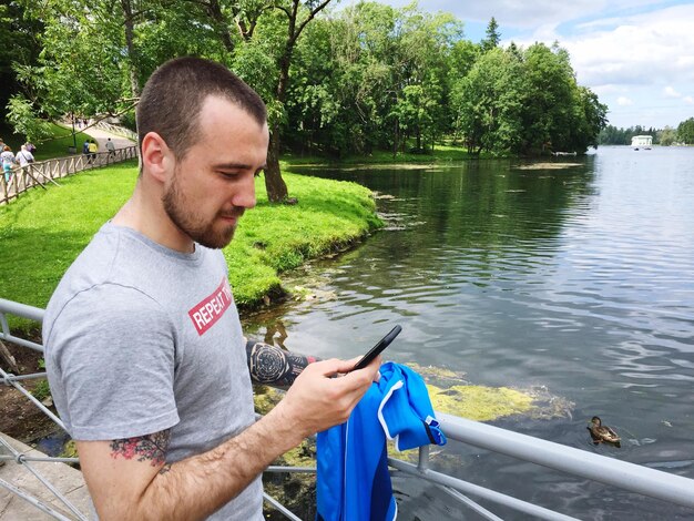 Mężczyzna używający telefonu komórkowego przy jeziorze